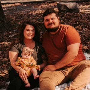 A family sits outside on a blanket in fall